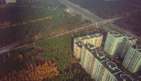 Golden autumn cityscape, aerial drone view of city skyline and forest with yellow trees and...