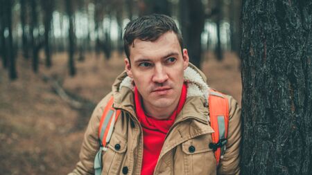 A traveling man with map in woods. A portrait of the handsome man with a backpack, standing near a...