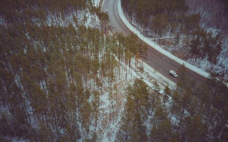 Cars on road in winter with snow covered trees aerial view.