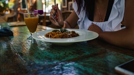 From above tasty fresh noodles on white plate and orange juice in glass