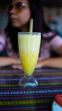 Healthy smoothie in tropical cafe. Cool fresh juice or cocktail with straw on tableの写真素材