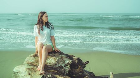 Female tourist resting on sandy beach near waving sea.の写真素材