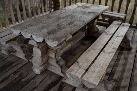 Fenced terrace with log table and benches in empty park during gloomy autumnal dayの写真素材