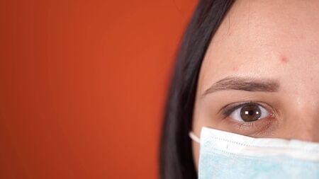 A Woman With a Medical Mask On his Face on an Orange Background.の写真素材