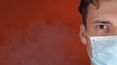 Adult guy covered his face with mask from smoke. Concept of anti-smoking.