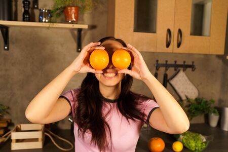Adult lady flirting and looking out of oranges at camera.の写真素材
