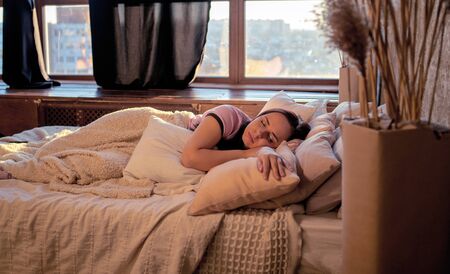 Adult charming female sleeping on pile of pillows.