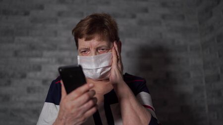 woman with a medical mask, learns the news about coronavirus from the Internet using a smartphone.