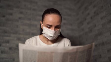 A woman with a medical mask, she hears the news about the coronavirus is from the newspaper.の写真素材