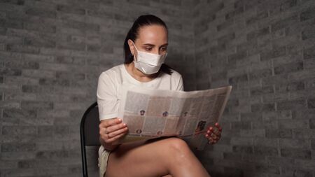 A woman with a medical mask, she hears the news about the coronavirus is from the newspaper.の写真素材