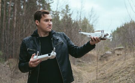Adult guy going to launch his drone in woodland.