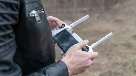 Close-up of men's hands going to launch his drone in woodland.