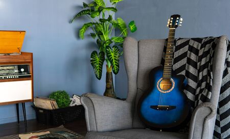 Close-up of comfortable armchair with plaid and guitar in room.の写真素材