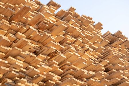 Pine wood timber stack of natural rough wooden boards on building site. Industrial timber building...