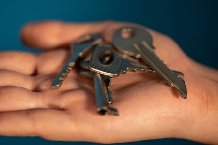 Huddle of keys on woman's palm on blue background.の写真素材