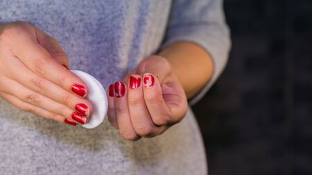 Woman hand removing red nail polish with white cotton pad.の写真素材
