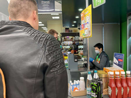 Voronezh, Russia April 29, 2020: Seller cashier in medical mask and gloves sitting behind box office...