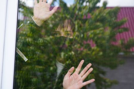 Thoughtful female with brown eyes observing through window.の写真素材