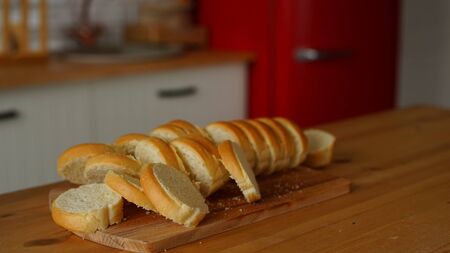 Chopped white bread on wooden board on kitchen table.