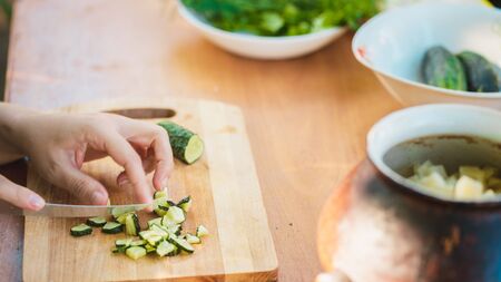 Close-up of women's hands cutting vegetable with knife on chopping board.の写真素材