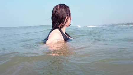 Woman waiting for sea wave. Side view of wet female swimming in sea water and waiting for foamy wave...