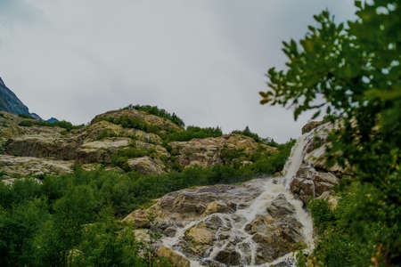 Rapid water stream falling from rocks against blue sky on sunny summer day in countrysideの写真素材