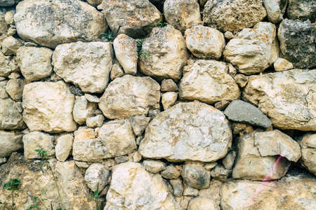 Texture of old stones of various forms with seams. Close up of shabby masonry. Stone wall from...