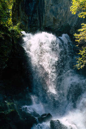 Amazing waterfall in forest in summer. Spectacular scenery of fast waterfall flowing down into river...