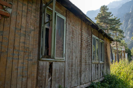 Window with broken glass in old building. Wooden window frame with partially broken glass in old abandoned wooden buildingの写真素材