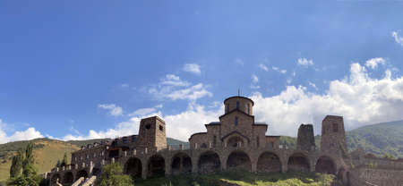 Old stone church on background of blue sky with white clouds. Architecture of monastery from uneven different ancient cobblestonesの写真素材