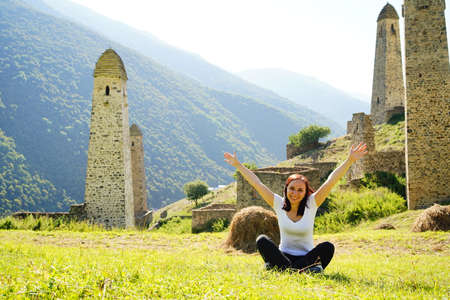 Carefree traveling woman relaxing on green lawn. Serene female tourist with backpack sitting on...