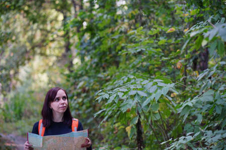 Traveling woman with map in woods. Woman with backpack walking in woods. Female carrying backpack...