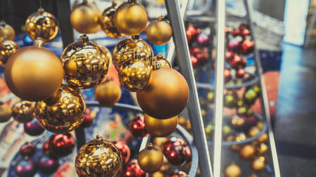 Close up of christmas toys suspended on metal construction in hall in shopping center. Yellow christmas balls hanging on strings for room decoration and create festive moodの写真素材