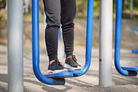 Portrait of woman's legs on street simulator in park. Close up of body part of female doing sports on athletic field in autumn season.の写真素材