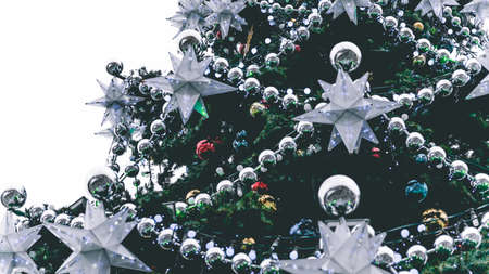 Close up of big Christmas tree with different christmas toys and decorative adornments on street. Coniferous tree with garland, beads and stars to create festive mood during holiday celebration.の写真素材