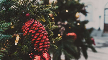 Close up of part of Christmas tree with different christmas toys and garland on street in evening city. Coniferous tree with decorative decorations to create festive moodの写真素材