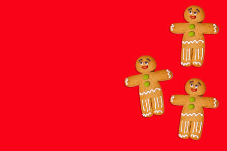 Close up of gingerbread men on red background. Festive decorative gingerbreads for Christmas mood...
