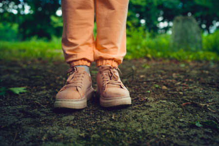 Close up of woman's feet in shoes on ground. Woman in pink sneakers stands in park in summertimeの写真素材
