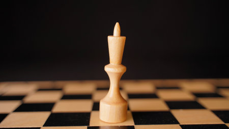 Close up of white chess piece on board. Wooden figure of king on chessboard on black background. Concept of intelligent, logical and strategic gameの写真素材