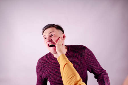 Crop person slapping scared man in face. Emotional male getting slapped in face while shouting with...