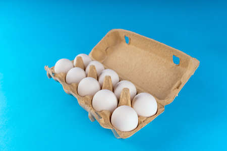 Farm raw, fresh white chicken egg in an egg box on a blue background. Eggs in carton. Eggs in the basket. Concept: a fresh egg for the morning breakfastの写真素材