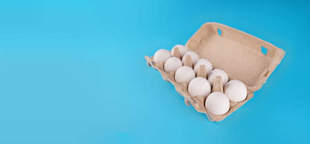Farm raw, fresh white chicken egg in an egg box on a blue background. Eggs in carton. Eggs in the basket. Concept: a fresh egg for the morning breakfastの写真素材