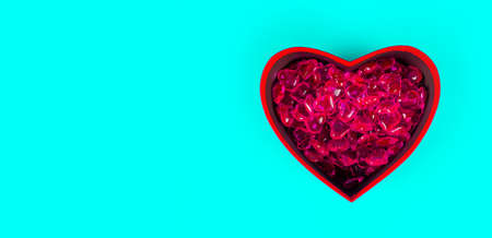 Close up of lots of hearts in red gift box in form of heart. Small red hearts in box for present on blue background. Concept of goodness, love and charity.の写真素材