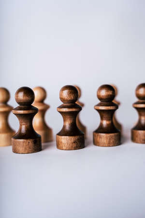 Close up of rows of black and white wooden chess pieces on white background. Selective focus on black pawnsの写真素材