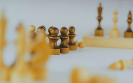 Close up of rows of black and white wooden chess pieces on white background. Selective focus on black pawnsの写真素材