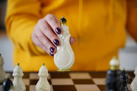 Selective focus of beautiful chess on chessboard. Close up of body part of unrecognizable woman playing in board gameの写真素材