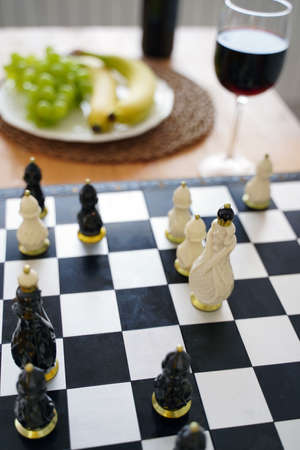 Close up of beautiful chess on table in kitchen. Selective focus of porcelain chess pieces on chessboardの写真素材