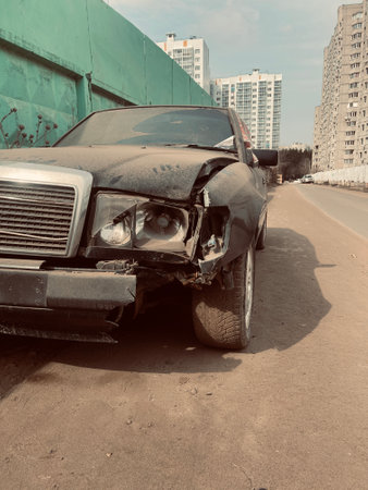 Close up of broken car on side of road. Damaged bumper, headlight and bodywork of black car after accident. Concept of careless driving.の写真素材