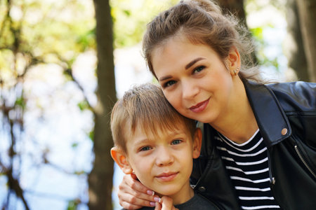 Portrait of mother and her little son on walk in countryside. Close up of young woman with child in natureの写真素材