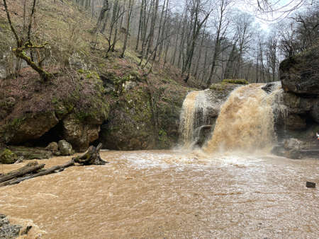 Beautiful landscape of powerful muddy waterfall in mountainous terrain. Dirty mountain waterway...
